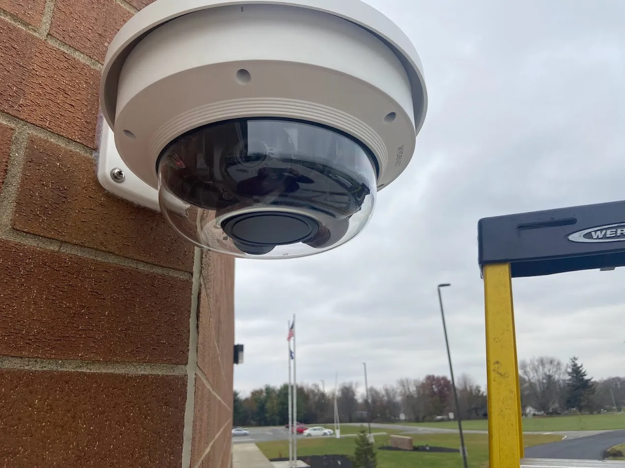 Exterior dome security camera on a brick school wall